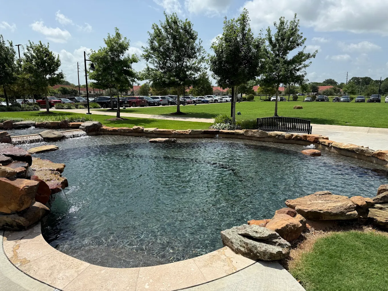Rock-edged water feature with a small waterfall on a landscaped commercial campus