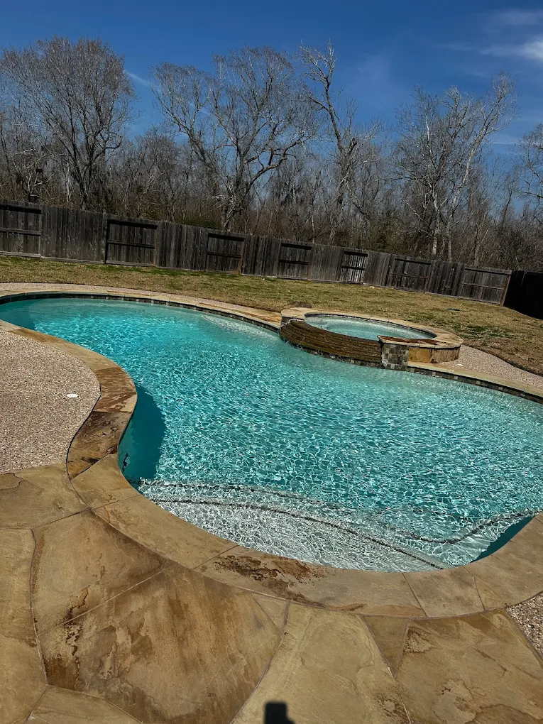 Freestyle backyard pool with an attached spa kept clean by Lanterra Pools