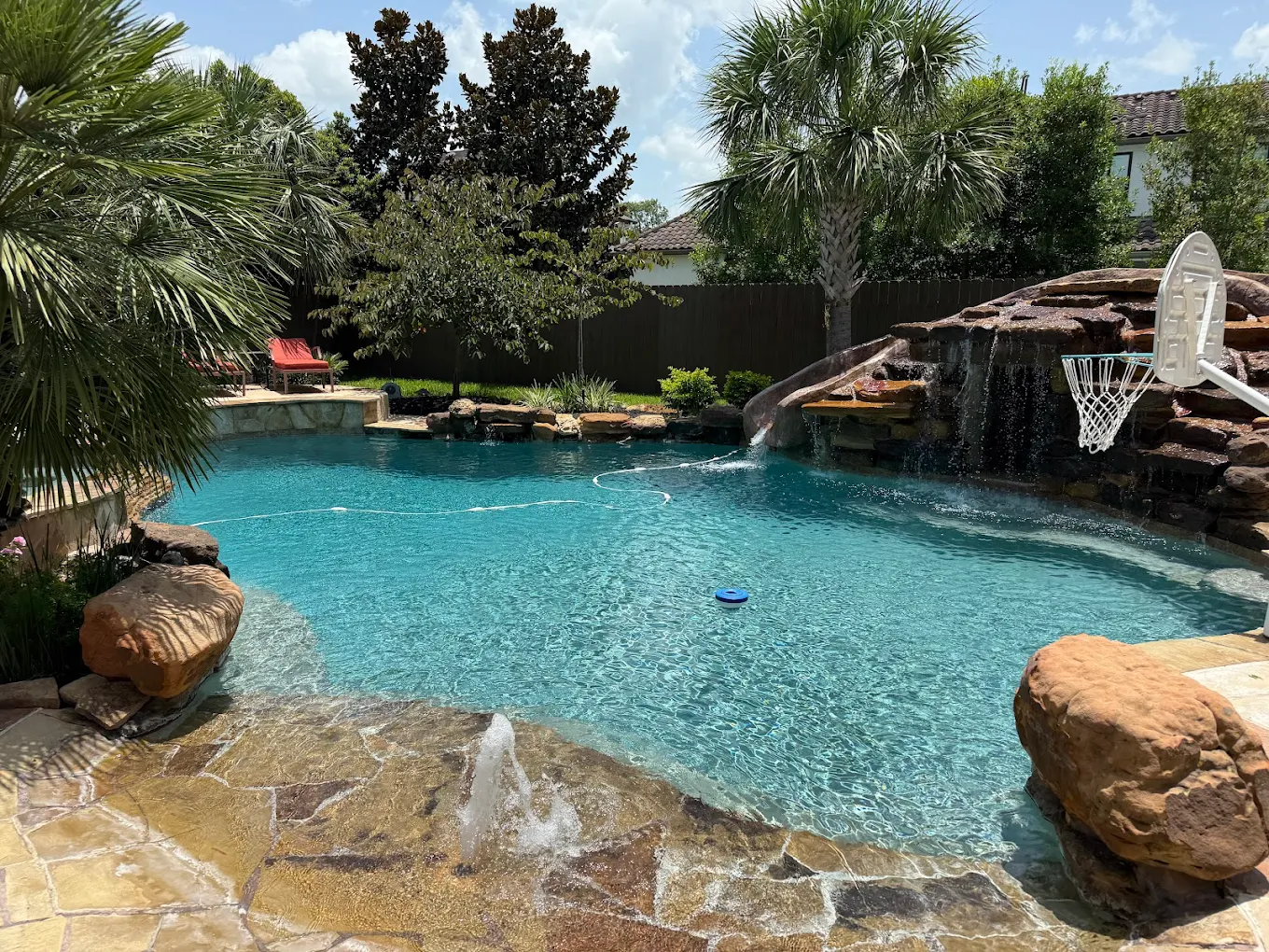 Resort-style backyard pool with a rock grotto waterfall and palm trees