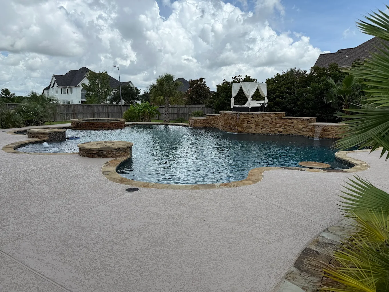 Freeform lagoon pool with a rock waterfall and a raised spa