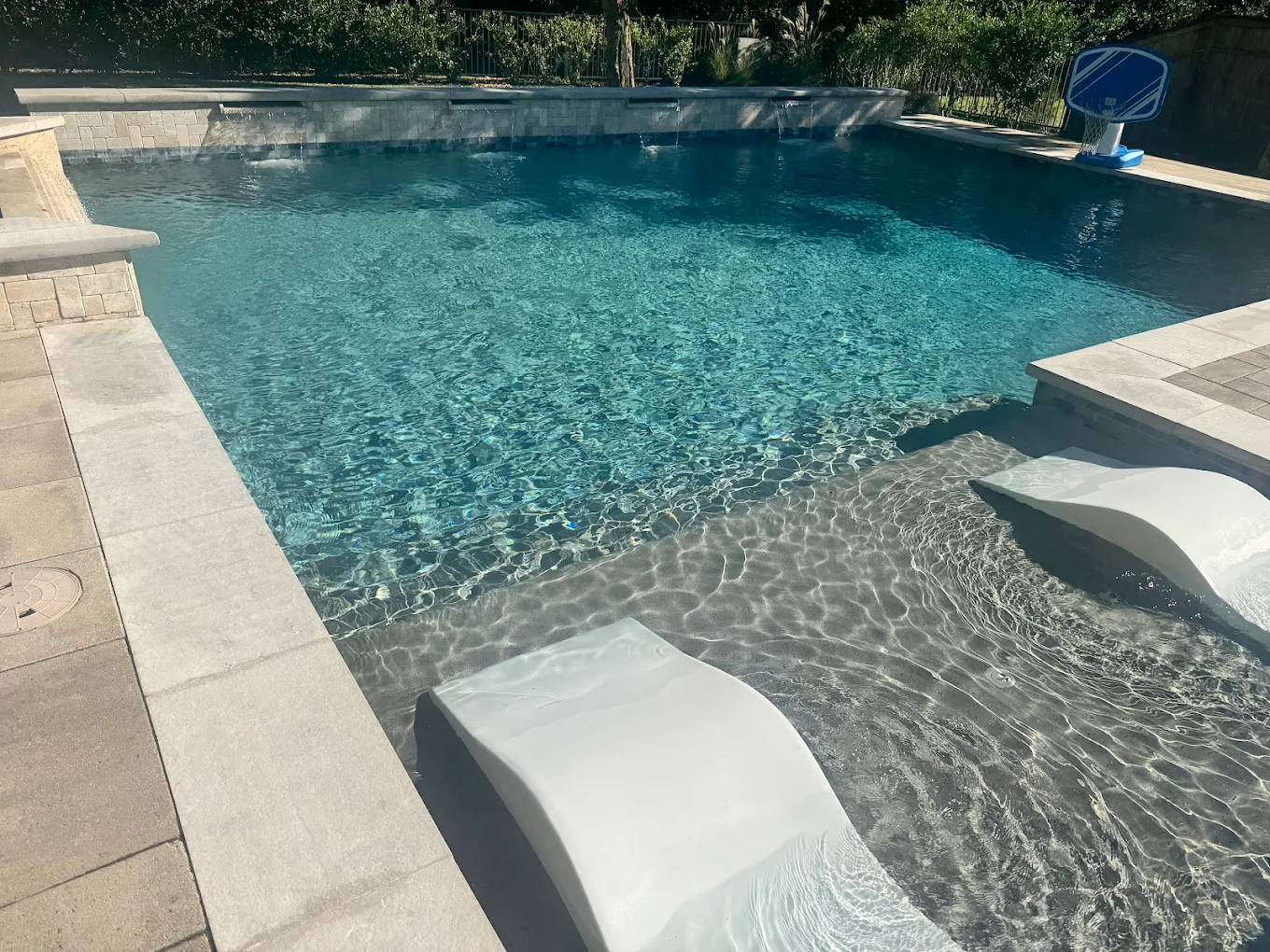 Modern pool with an in-water tanning ledge and lounge chairs