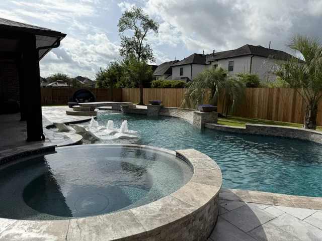 Round raised spa with tanning-ledge bubblers on a travertine pool deck