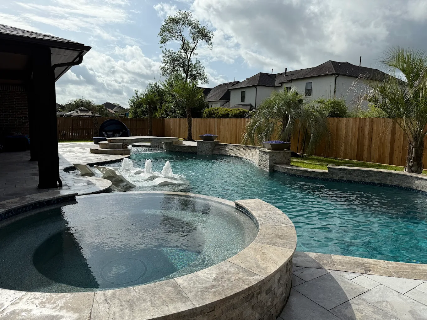 Pool with a raised spa and deck-jet water features on travertine