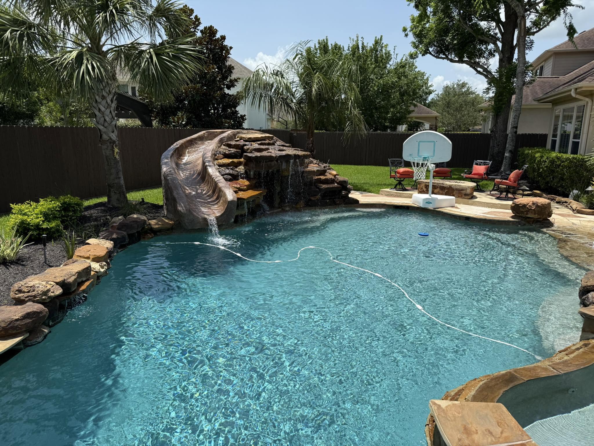 Clean backyard pool water with rock waterfall maintained by Lanterra Pools